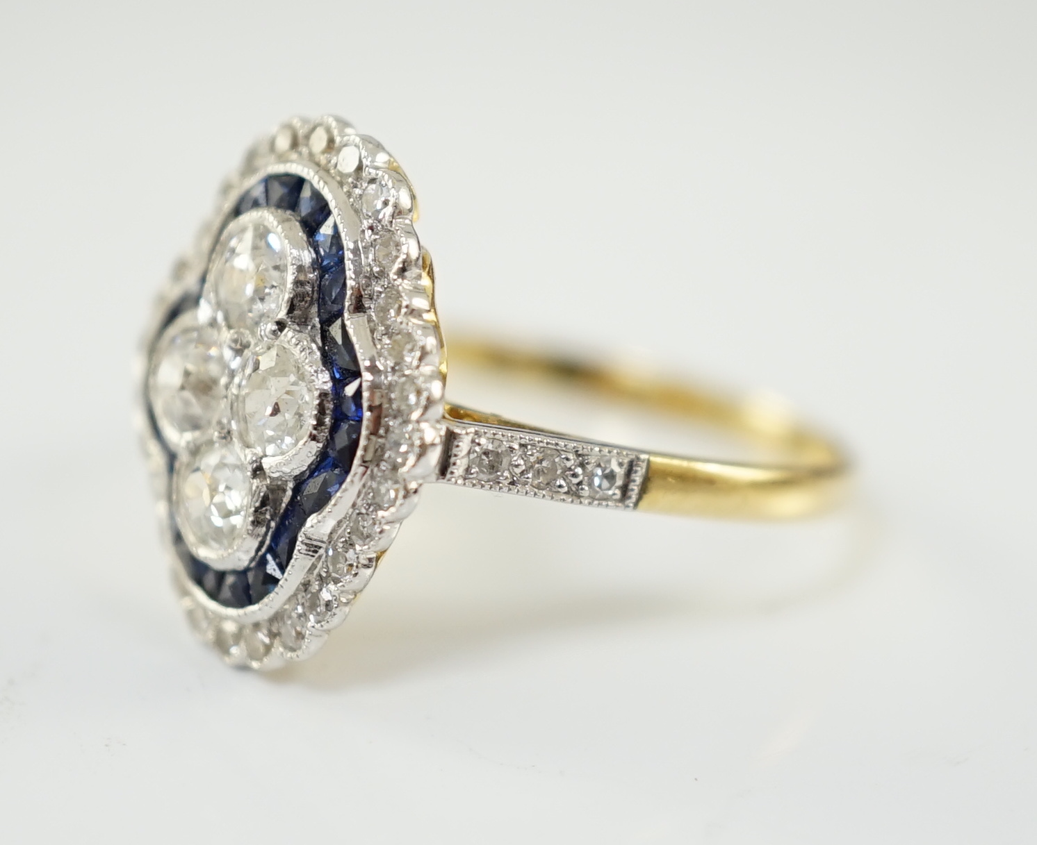 A modern 18ct gold, sapphire and diamond set quatrefoil shaped cluster ring